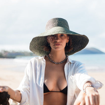 Woman in a wide-brimmed hat and black bikini top on a beach