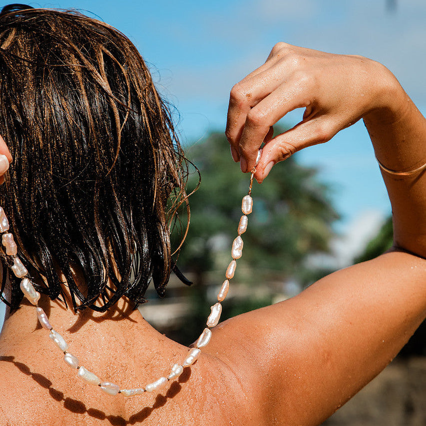 Person with a beaded necklace against a natural background
