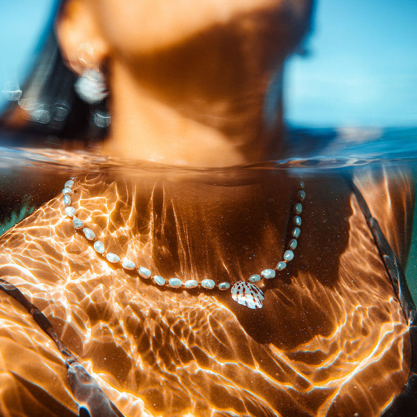 Person underwater wearing a necklace with a clear blue background
