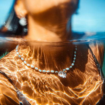 Person underwater wearing a necklace with a clear blue background