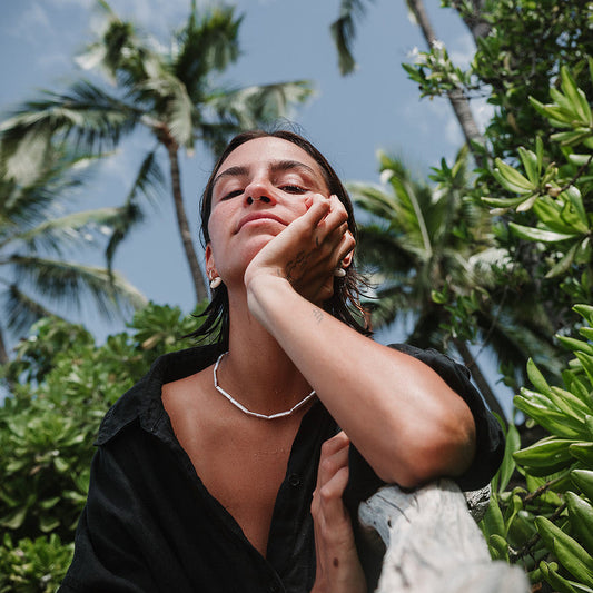 Woman with a serene expression surrounded by tropical foliage