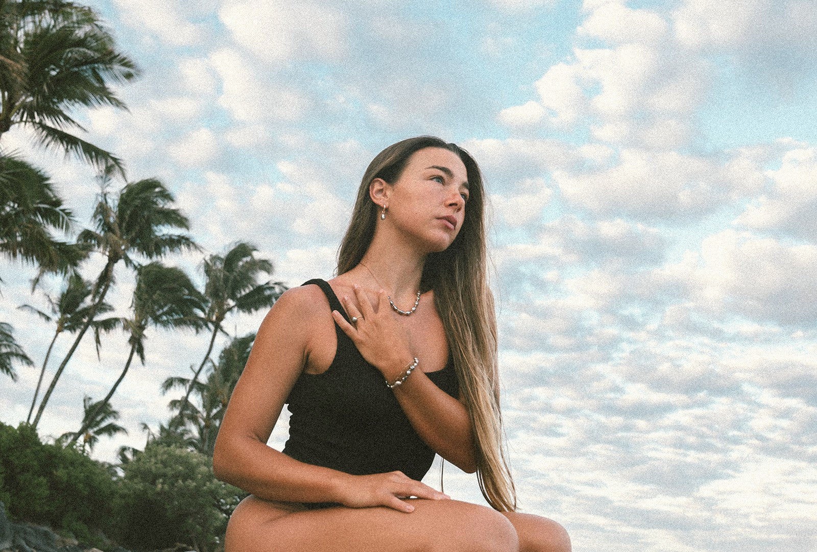 Woman wearing handcrafted Studio Immersed shell and pearl jewelry on the beach, Wear the Ocean's Light hero image