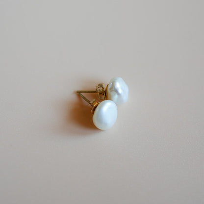 Pair of white earrings on a beige background