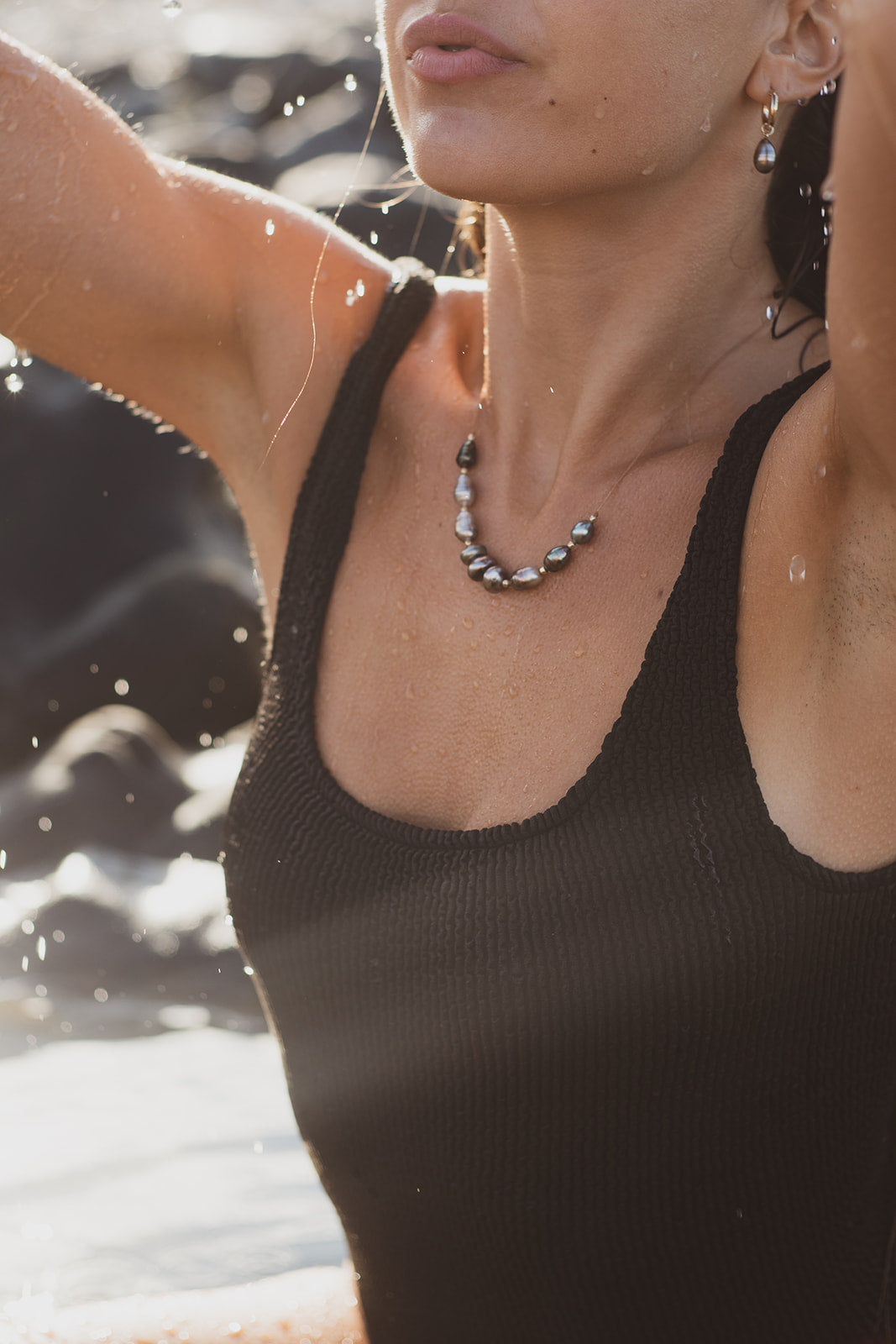 Close-up of Studio Immersed beaded necklace worn by model in swimwear